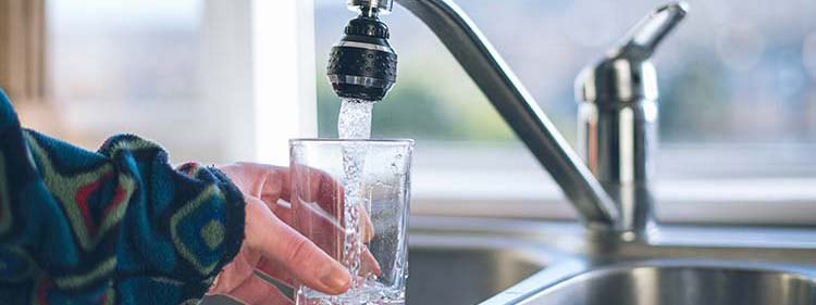 Glass of water being filled up at a kitchen tap